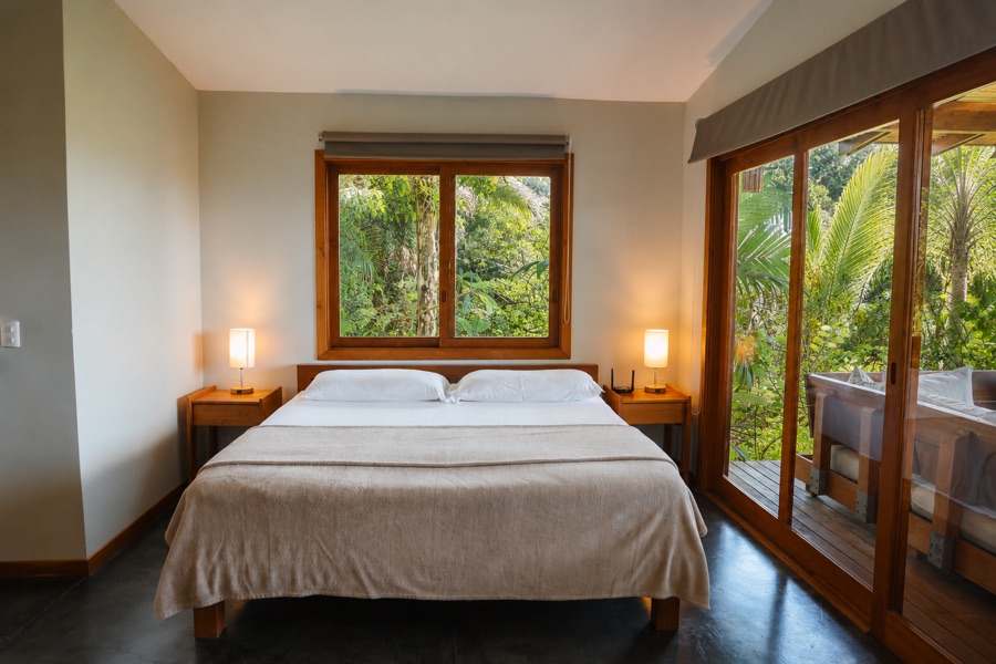 Sunrise Studio vacation rental in Montezuma, Costa Rica: king bed between a window and glass sliders to the deck